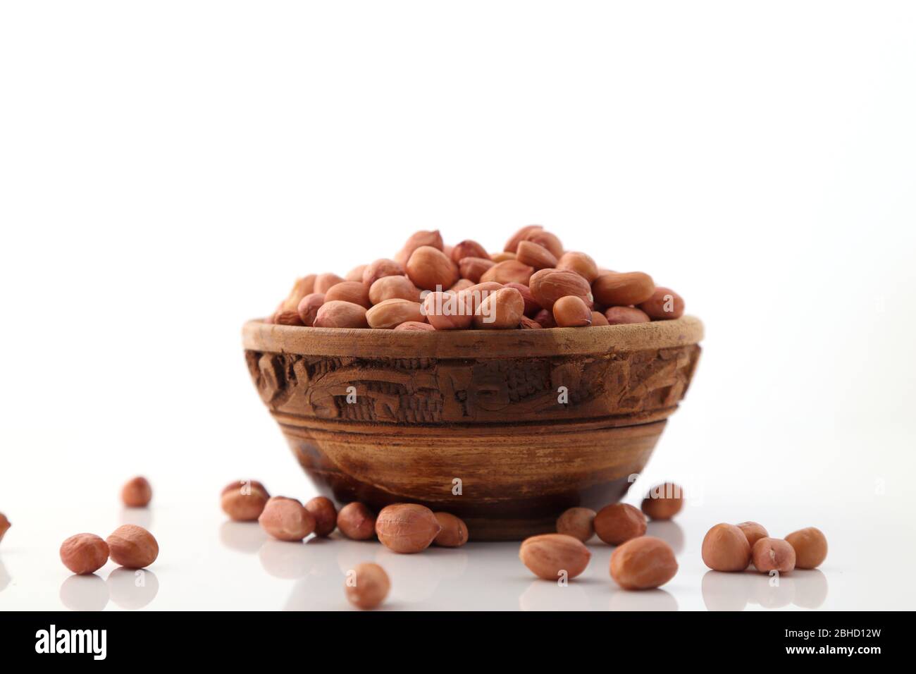 Rohe Erdnüsse oder Arachis in einer Holzschale auf weißem Hintergrund Stockfoto