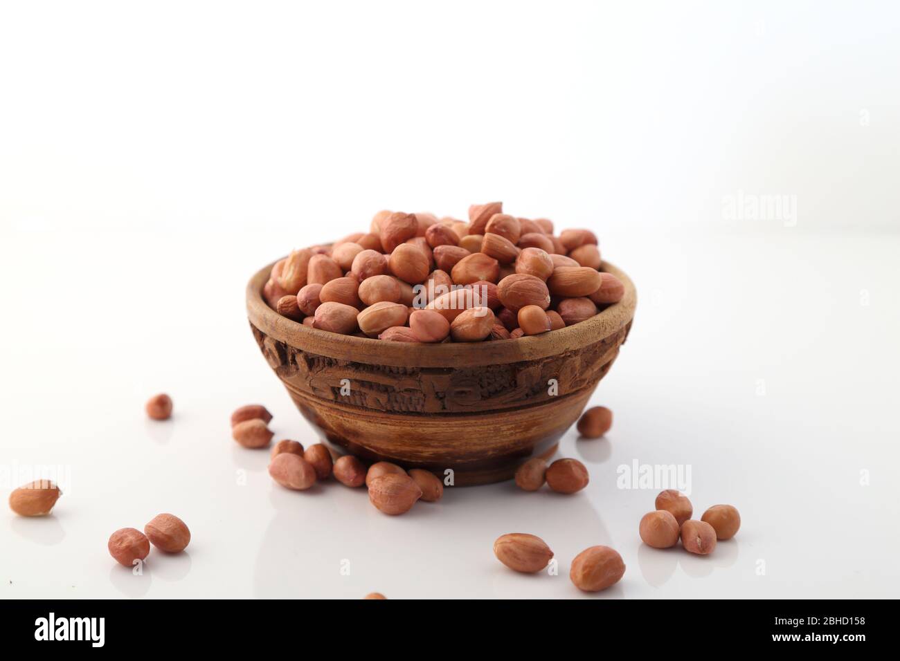 Rohe Erdnüsse oder Arachis in einer Holzschale auf weißem Hintergrund Stockfoto