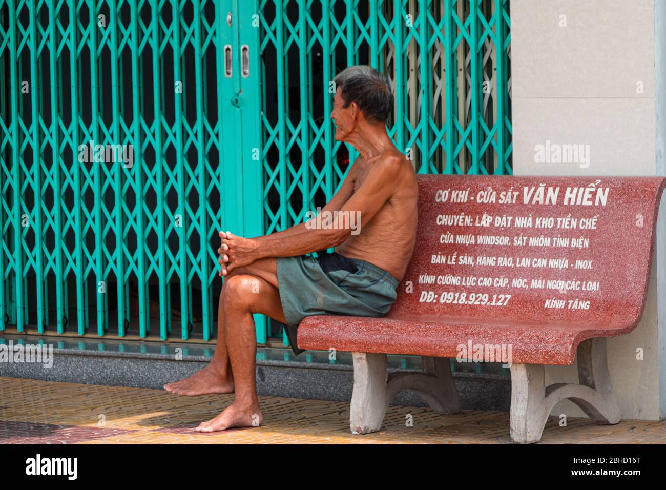 Profil von barfuß faltigen alten vietnamesischen Mann auf Bank sitzen, Sa Bec, Vietnam, Asien Stockfoto