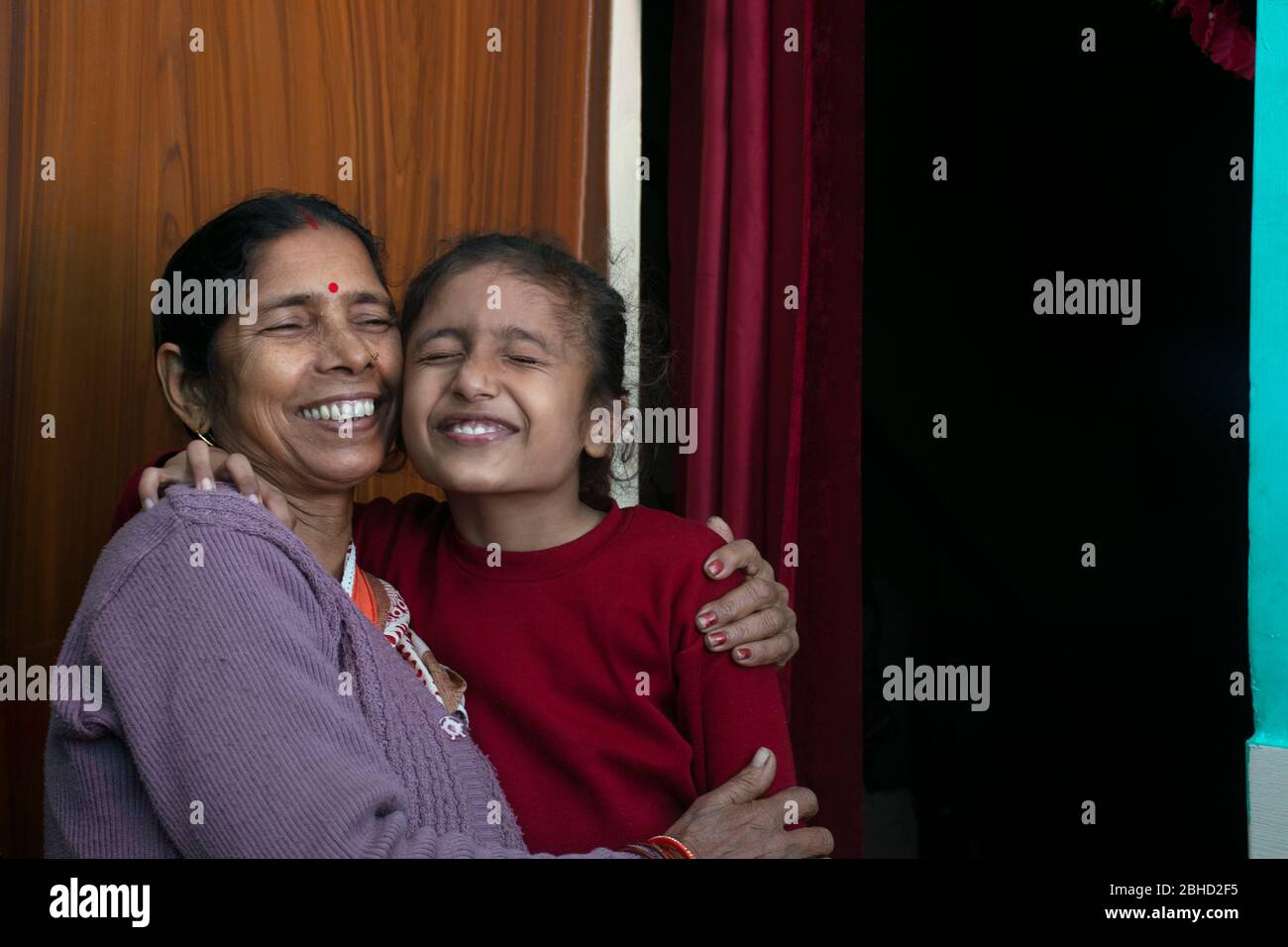Glückliche Großmutter und Enkelin umarmen einander, Indien Stockfoto
