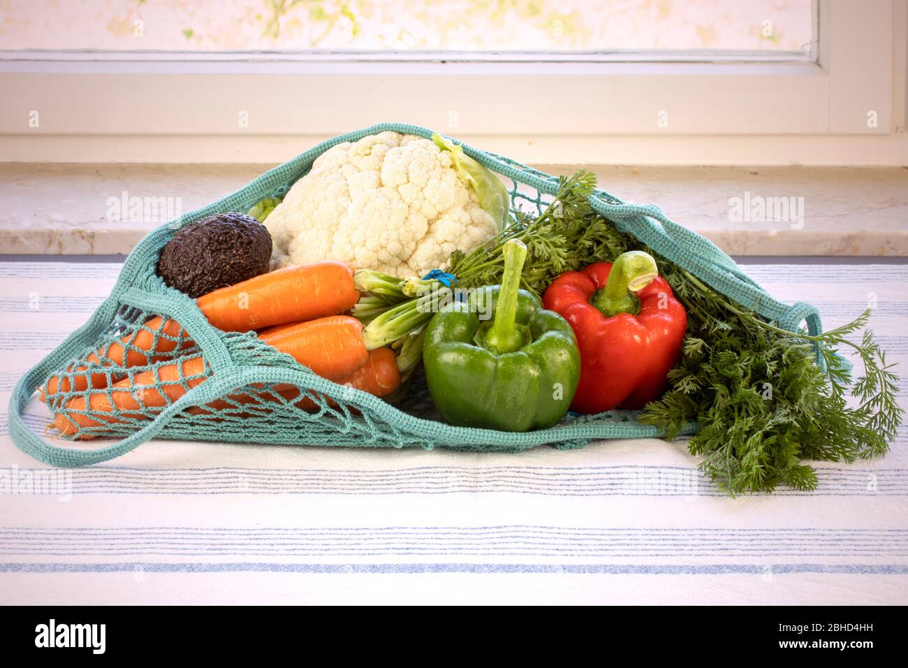 Frisches Gemüse in einem blauen Netzbeutel, wiederverwendbar, nachhaltig, umweltfreundlich, Erdtag, kein Plastikkonzept. Verschiedene Gemüse: Paprika, Karotten, Blumenkohl Stockfoto
