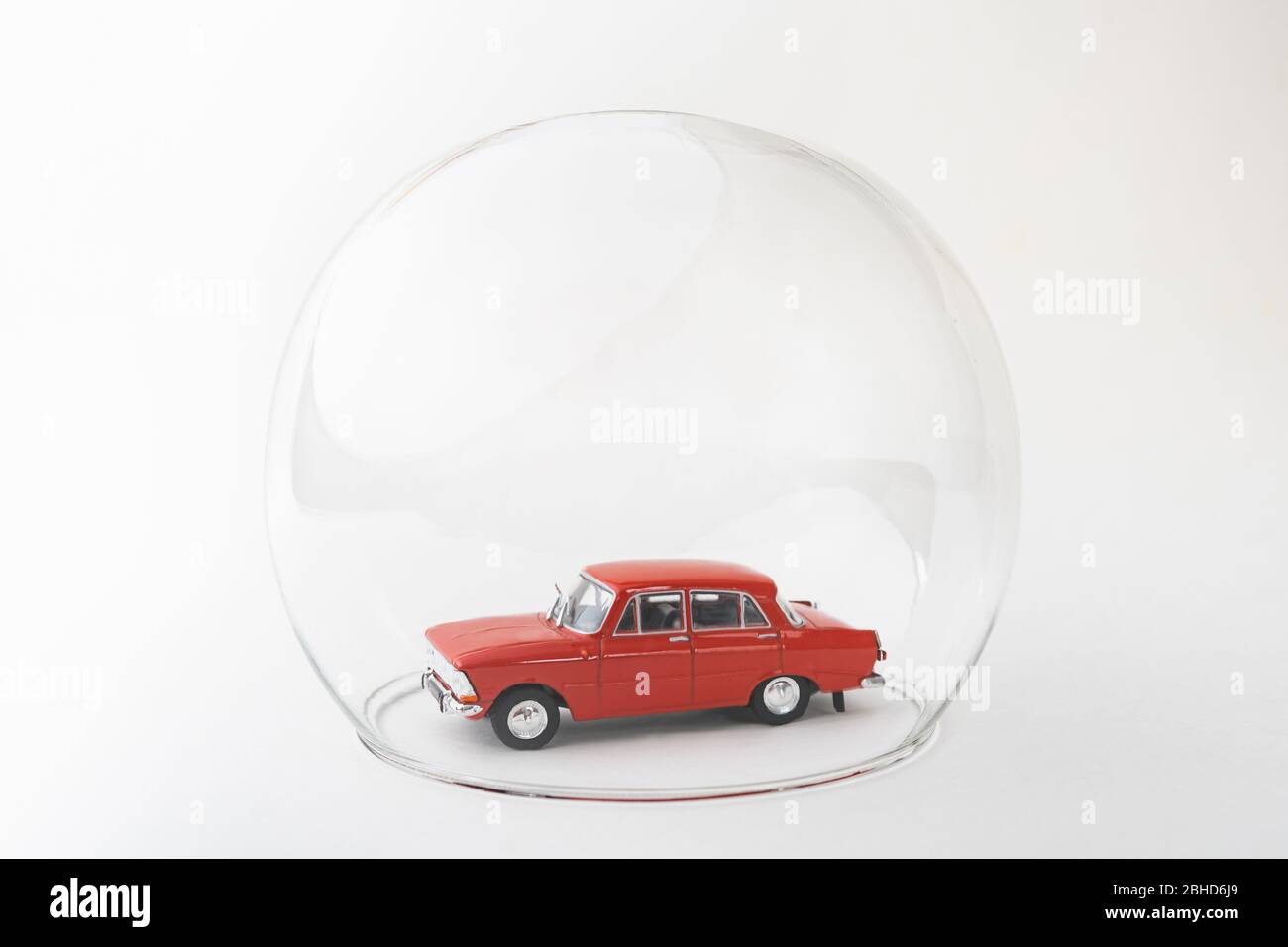 Rotes Spielzeugauto in einer Glaskugel. Konzeptionelles Bild des Versicherungsschutzes und des Sicherheitsschutzes. Stockfoto