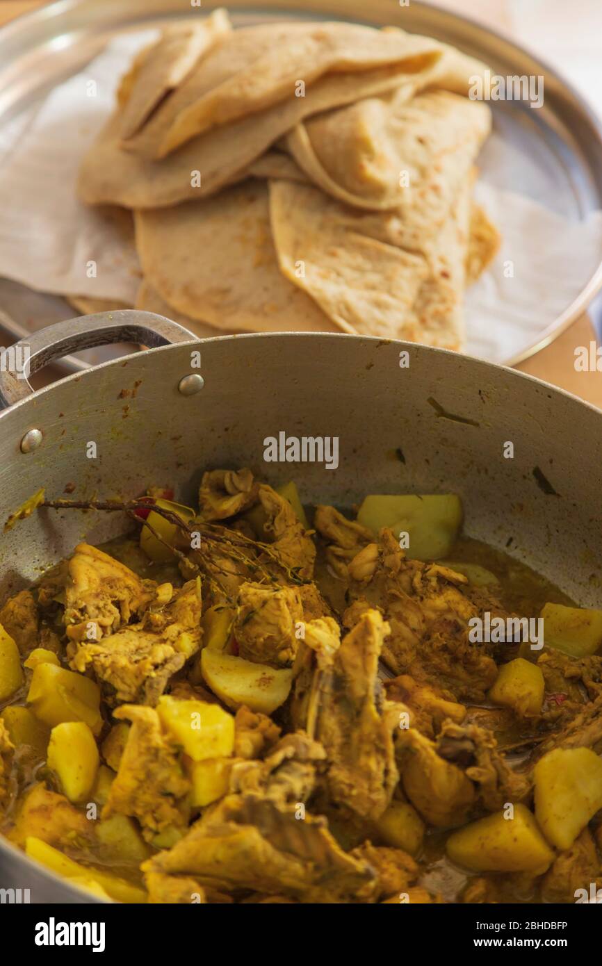 Dhal puri auf einem Tablett und Curry Huhn und Irish Kartoffeln in einem Eintopf in einem Topf Stockfoto