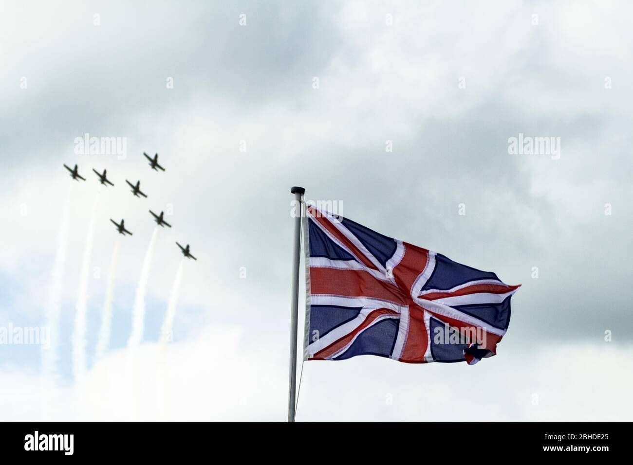 Flugzeuge fliegen in Formation an einer Union Jack Flagge vorbei Stockfoto