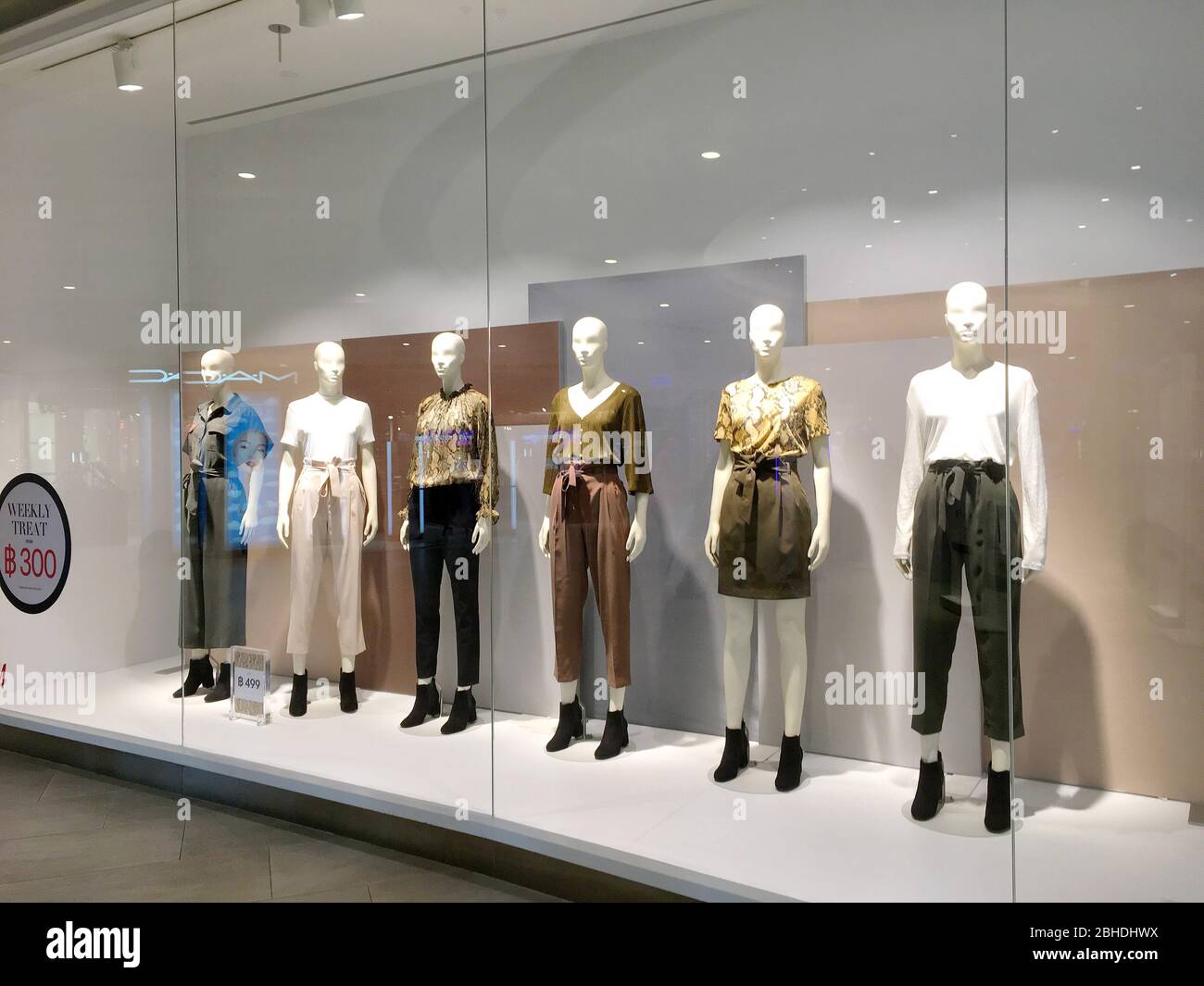 Die bekleideten H&M-Mannequins mit Damenmode und roten und weißen Bolloons im Glasfenster 