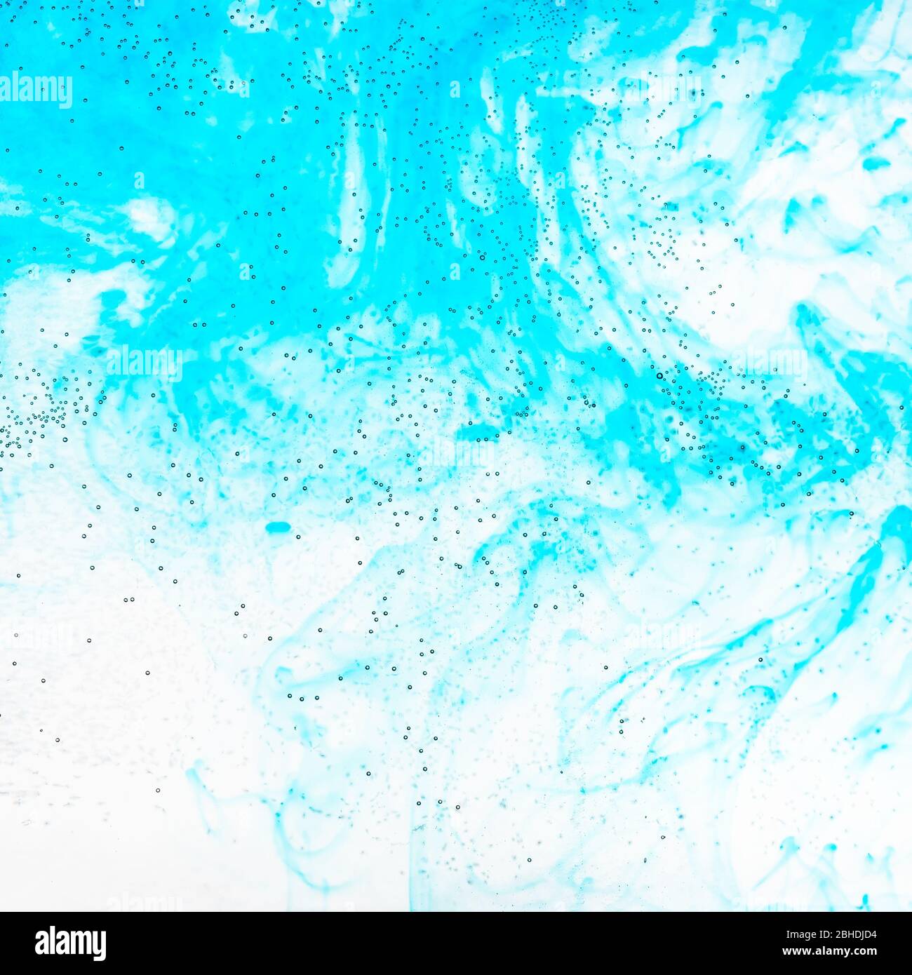 Luftblasen auf der Glasoberfläche der flachen Flasche und aquamarinfarbenen Aquarelle fließen im Wasser auf dem Hintergrund Stockfoto
