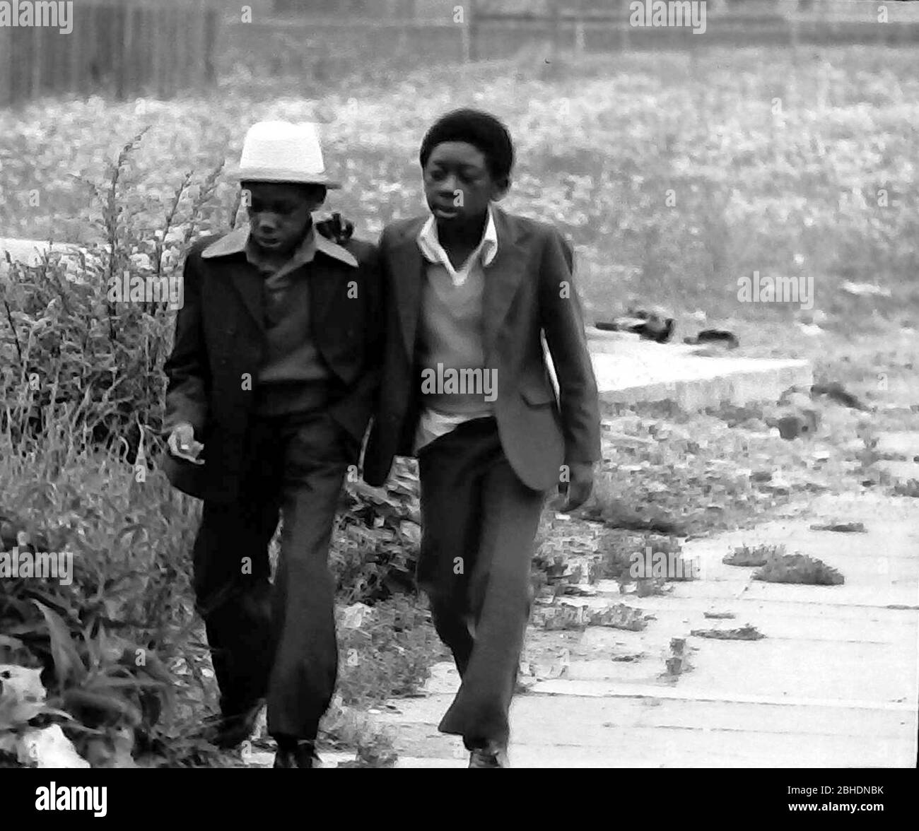 Das tägliche Leben auf den Straßen in Manchester, England, Großbritannien im Jahr 1974. Zwei junge, schwarze afro karibische Jungen gehen neben einem Gebiet von Abfallboden. Stockfoto