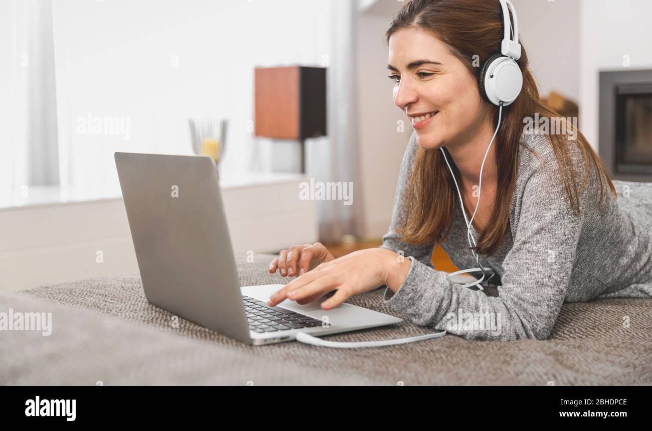 Schöne Frau mit Laptop beim Musik hören zu Hause arbeiten Stockfoto