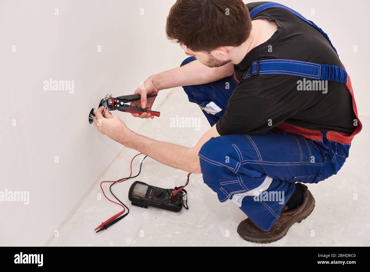 Hände Mann Anschluss Anschlussklemme Draht, halten Crimpzange. Designhintergrund. Professionelle Materialien. Elektroarbeiten. Männliches Hobby Stockfoto