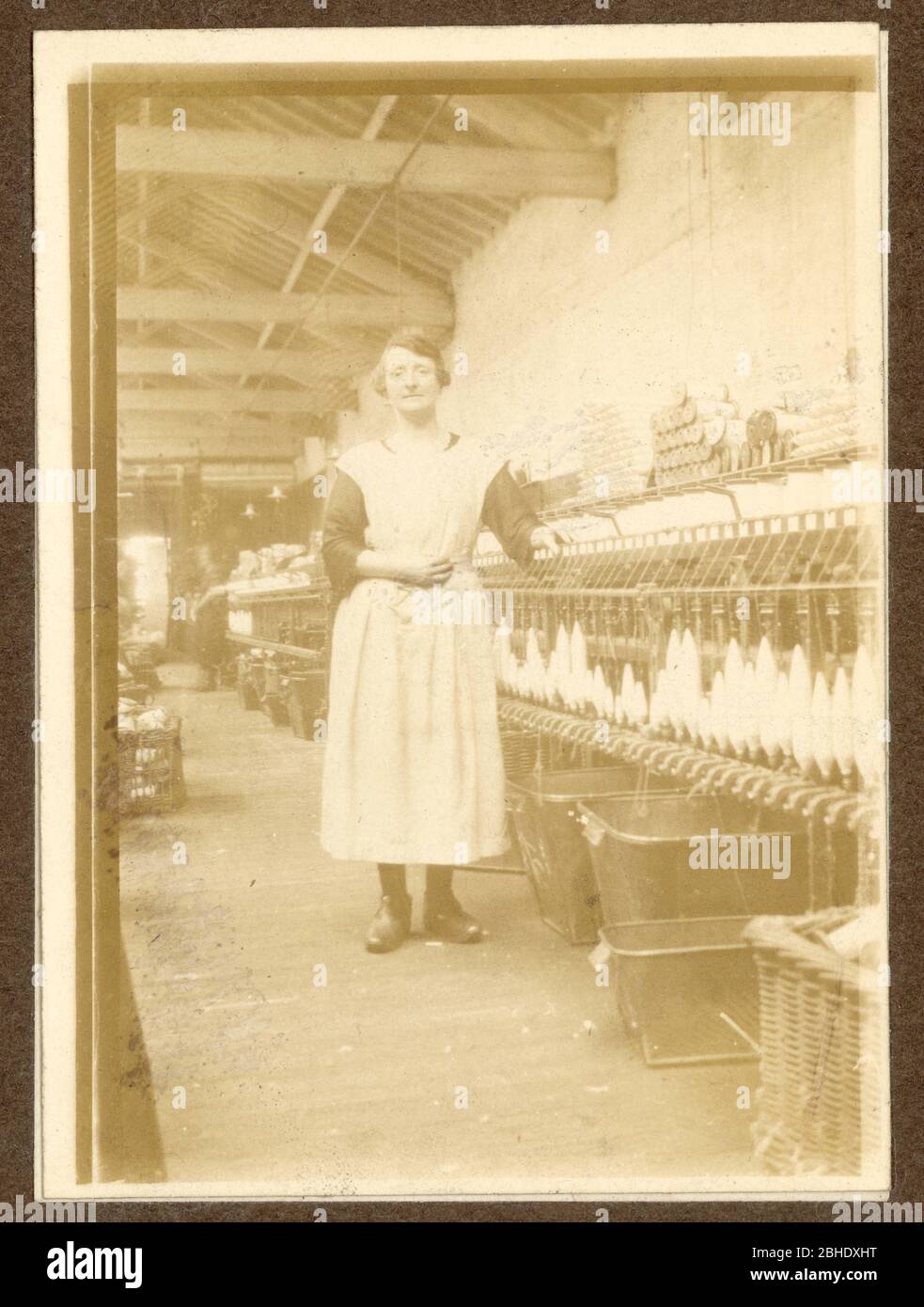 Foto des Lancashire-Baumwollspinners aus dem frühen 20. Jahrhundert, der neben einem Spinnerei in einer Baumwollfabrik steht und Clogs trägt, Radcliffe, Lancashire, Großbritannien um 1917 Stockfoto