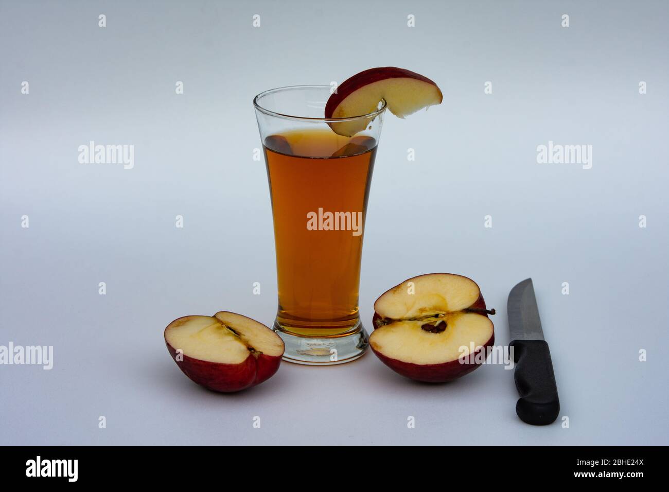 Ein Glas Apfelsaft mit in Scheiben geschnittenen roten Apfel auf weiß isoliert. Stockfoto