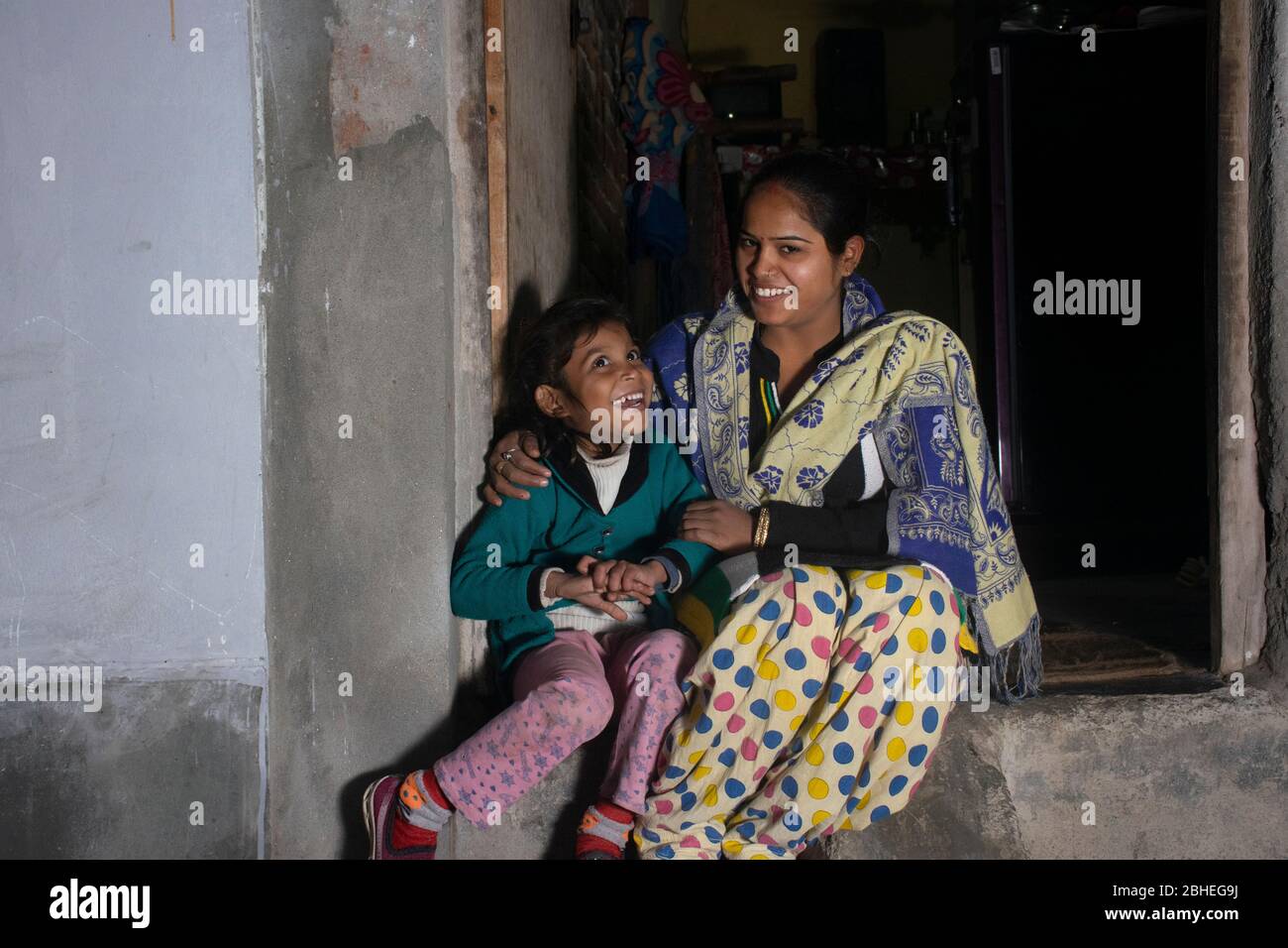 indische ländliche Mutter und Tochter sitzen vor der Tür des Hauses Stockfoto