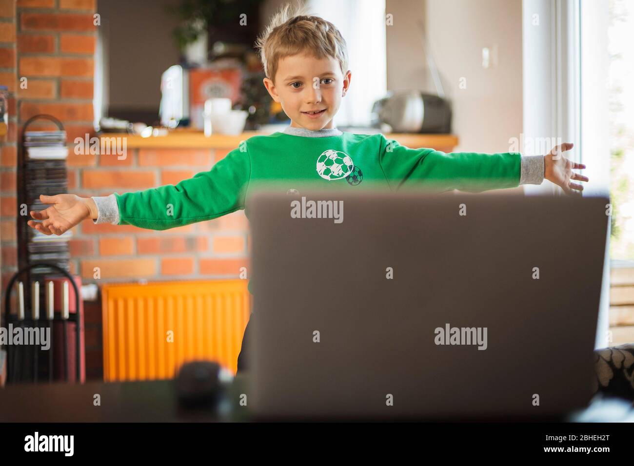 Der Junge übt zu Hause vor dem Computer als Teil einer Online-Sportunterricht wegen geschlossener Schulen wegen der Pandemie Coronaviru Stockfoto