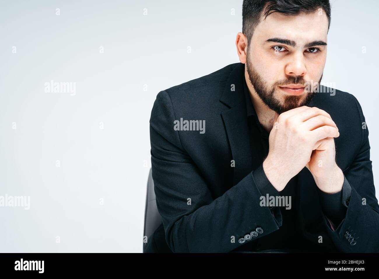 Junge schöne Mann mit Bart und Hand auf Kinn Denken über Frage, nachdenkliche Ausdruck. Nachdenkliche Gesicht. Zweifelskonzept. Stockfoto