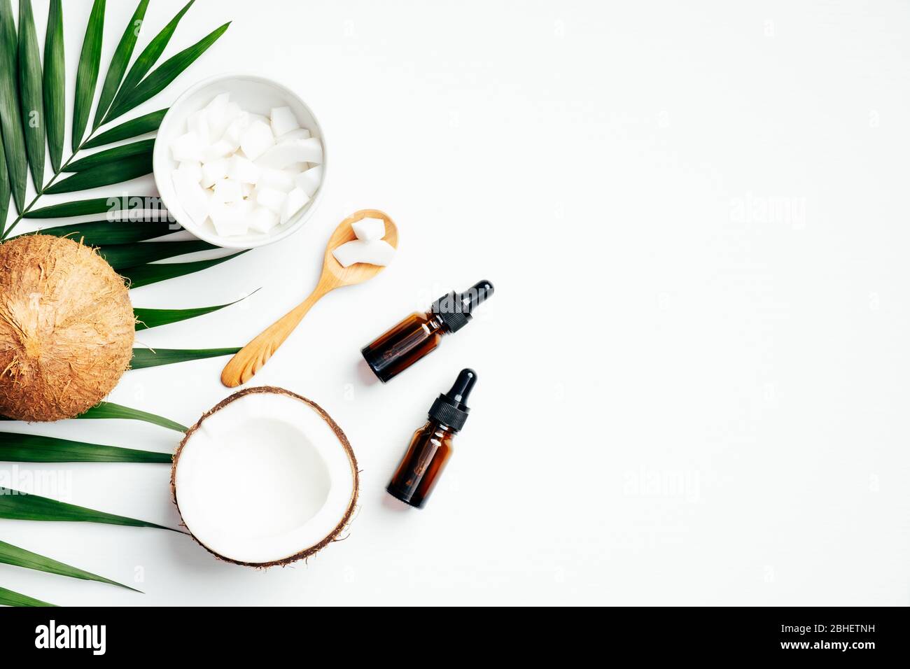 Kokosnuss-Schönheitsprodukte mit tropischen Palmenblättern auf weißem Hintergrund. Flaches Layout, Draufsicht, Kopierbereich. Hautpflege, Aromatherapie Massage Konzept Stockfoto