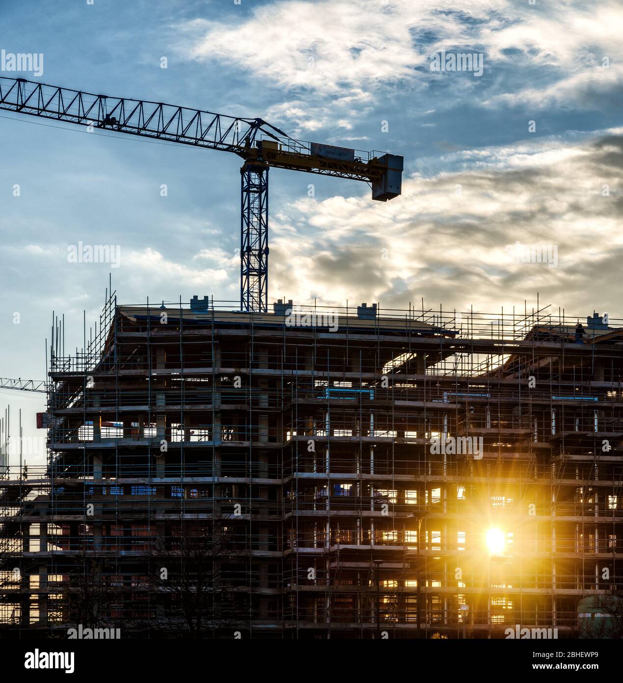 Gebäude Bau Baustelle Hof bei Sonnenuntergang mit Sonnenstrahlen und Wolken Stockfoto