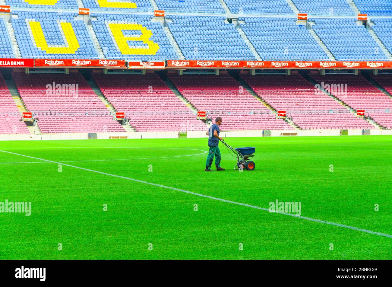 Barcelona, Spanien, 14. März 2019: Arbeiter sät Gras mit Düngerstreuer auf dem Rasen des Camp Nou Grünfeld, Tribunen steht im Hintergrund. Stadion des Fußballclubs Barcelona Stockfoto