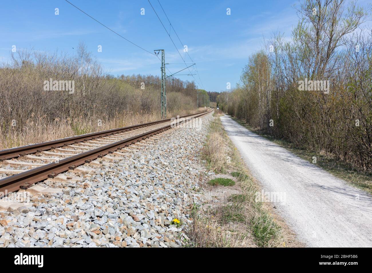 Gerader Blick auf einen Fußweg und Bahngleise. Die Gleise sind Teil des öffentlichen Verkehrsnetzes München. Konzept für Reisen, Reisen, weite Wege. Stockfoto