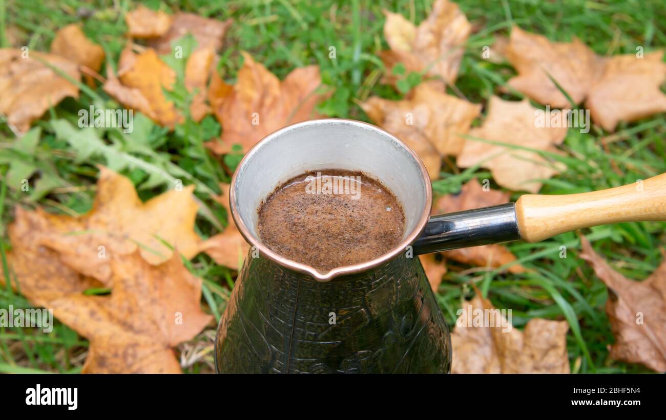 Kaffee in einer türkischen Kanne brauen - im Freien über die Herbstblätter Stockfoto