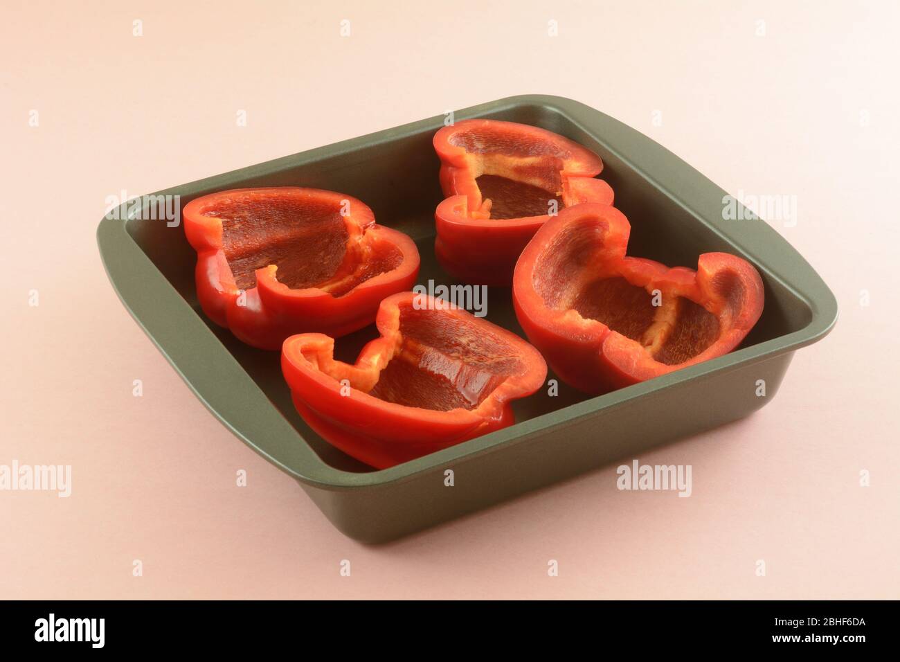 Frische rohe rote Paprika halbiert in Antihaft-Backform zum Kochen vor dem Stopfen Stockfoto