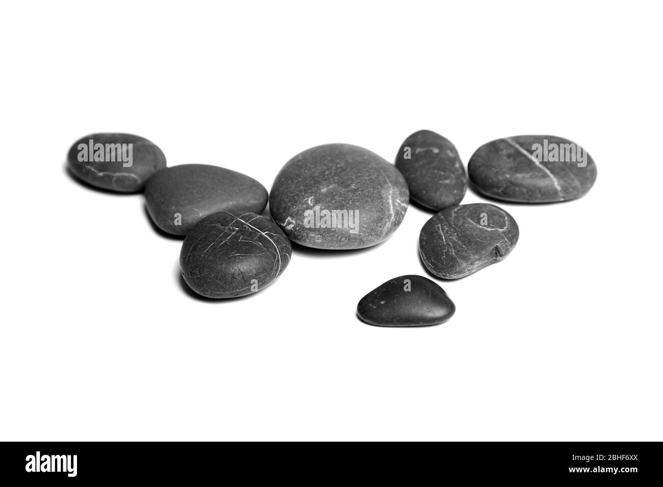 Schwarze Steine auf weißem Hintergrund isoliert. Haufen von glatten grauen und schwarzen Meerestieseln Stockfoto