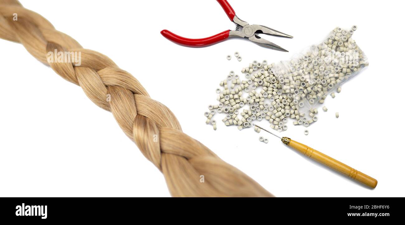 Frauen Haarverlängerung Zubehör und eine gefälschte blonde har Schwanz geflochten. Zangen, Rohre und ein lacer, isoliert auf weißem Hintergrund. Stockfoto