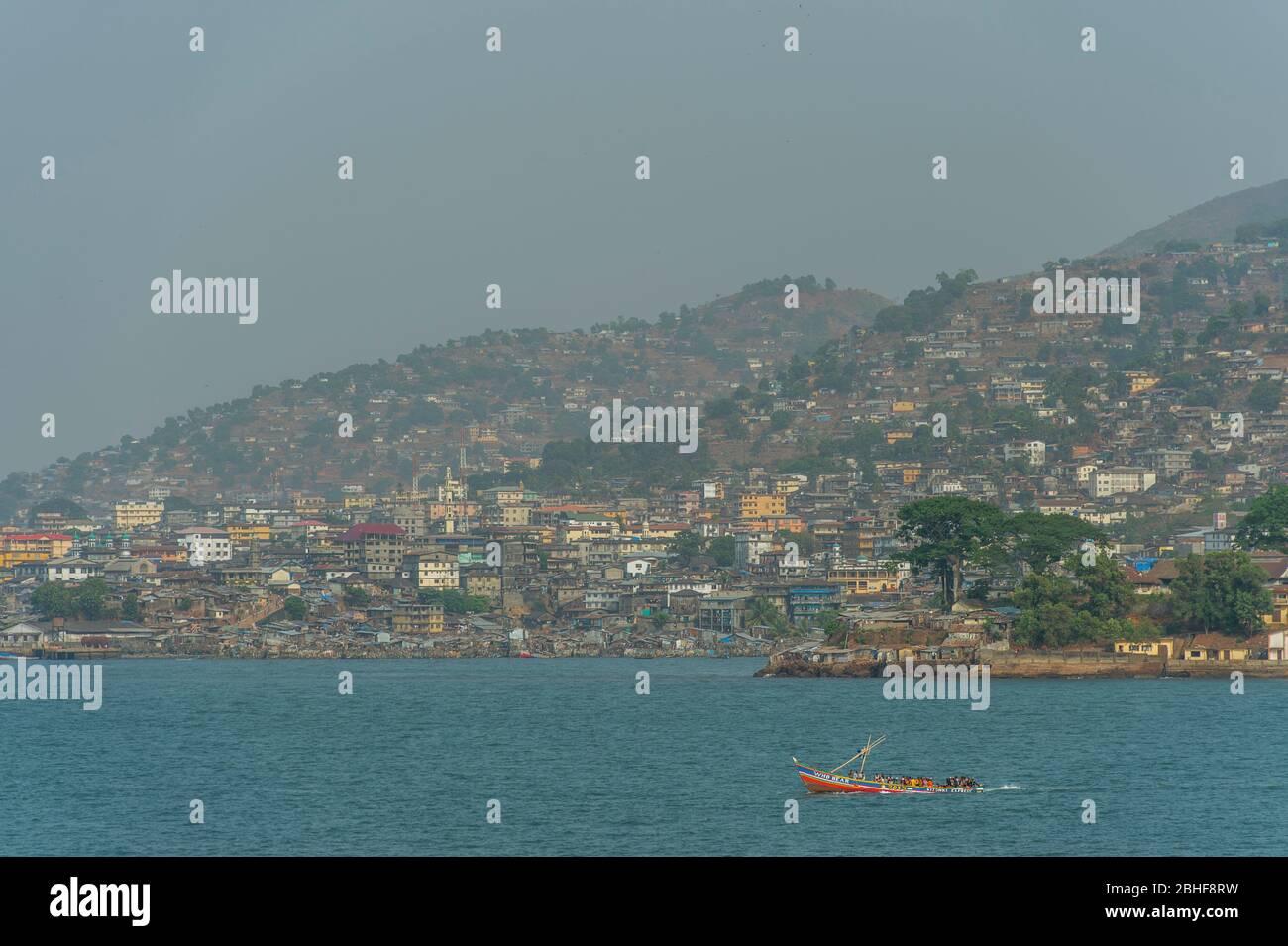 Blick vom Meer auf Freetown, die Hauptstadt von Sierra Leone mit kleinem Boot als Fähre. Stockfoto