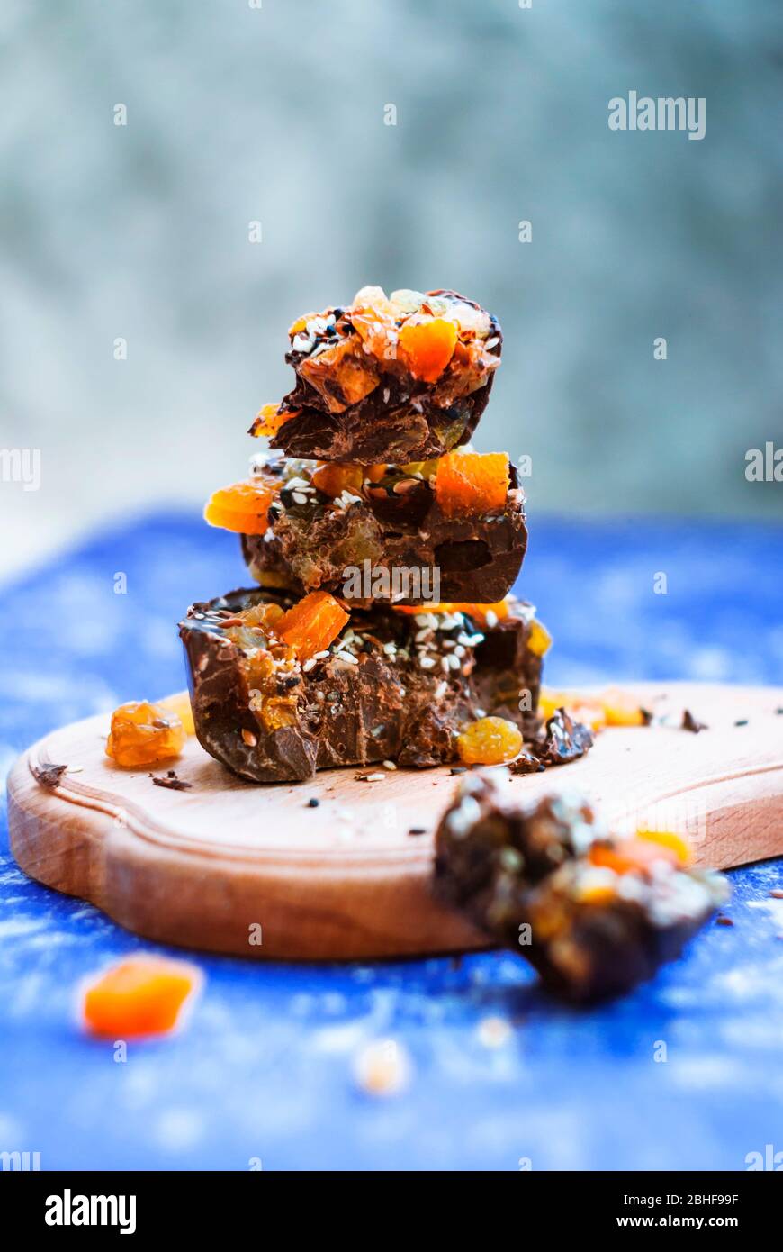 In Scheiben geschnittene Schokolade mit getrockneten Aprikosen, Rosinen, Leinsamen, Sesam ​​homemade. Auf blauem Hintergrund. Stockfoto