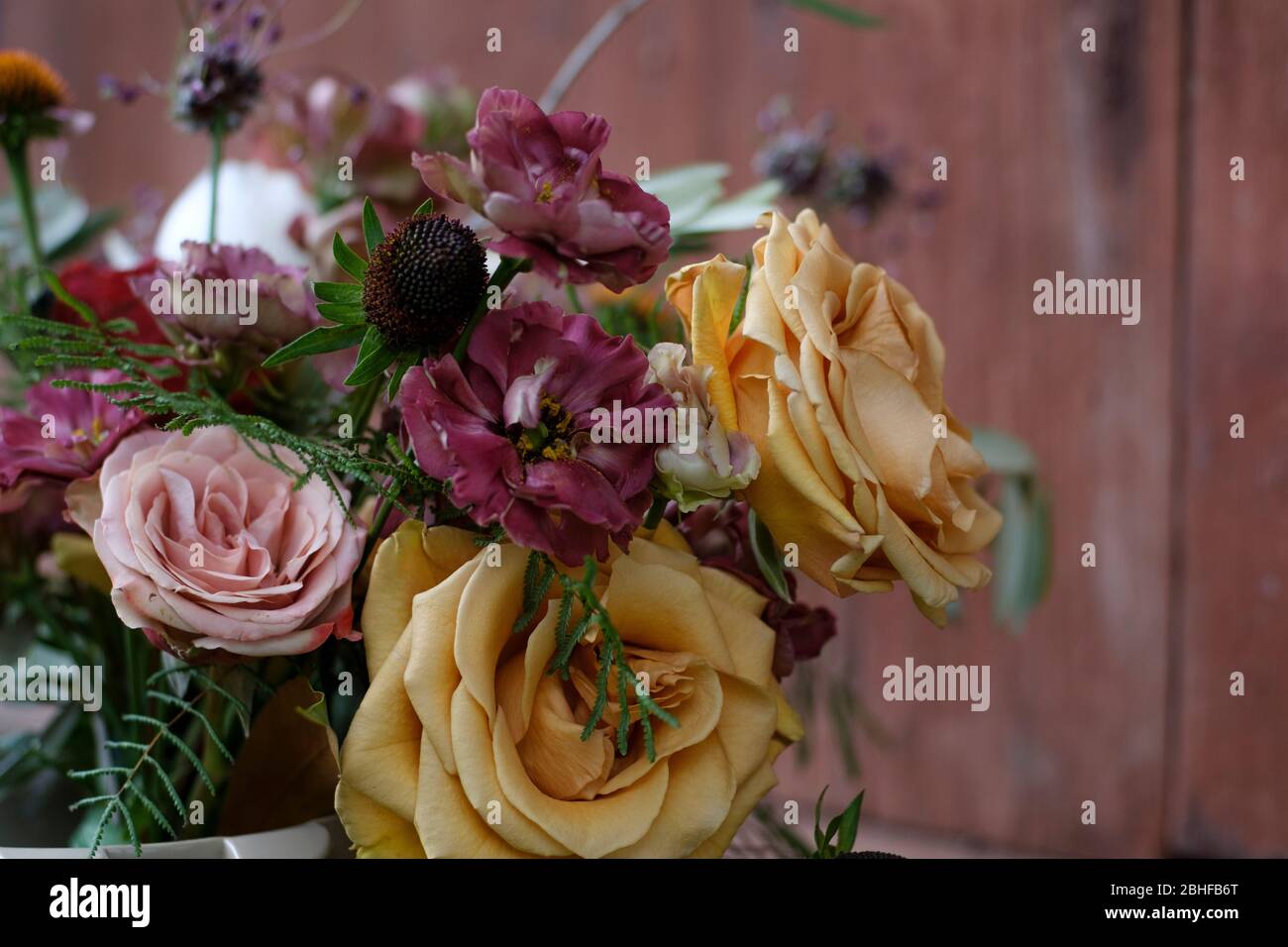 Schöner Strauß verschiedener Blumen in der Nähe auf einem braunen Hintergrund. Bouquet im Boho-Stil. Stockfoto