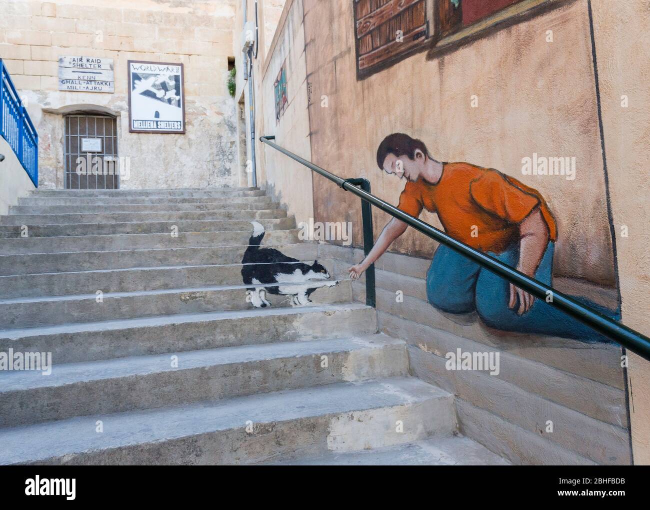 Bemalter Mann mit Katze auf Stufen, nur aus einem Winkel gesehen, Mellieha, Malta Stockfoto