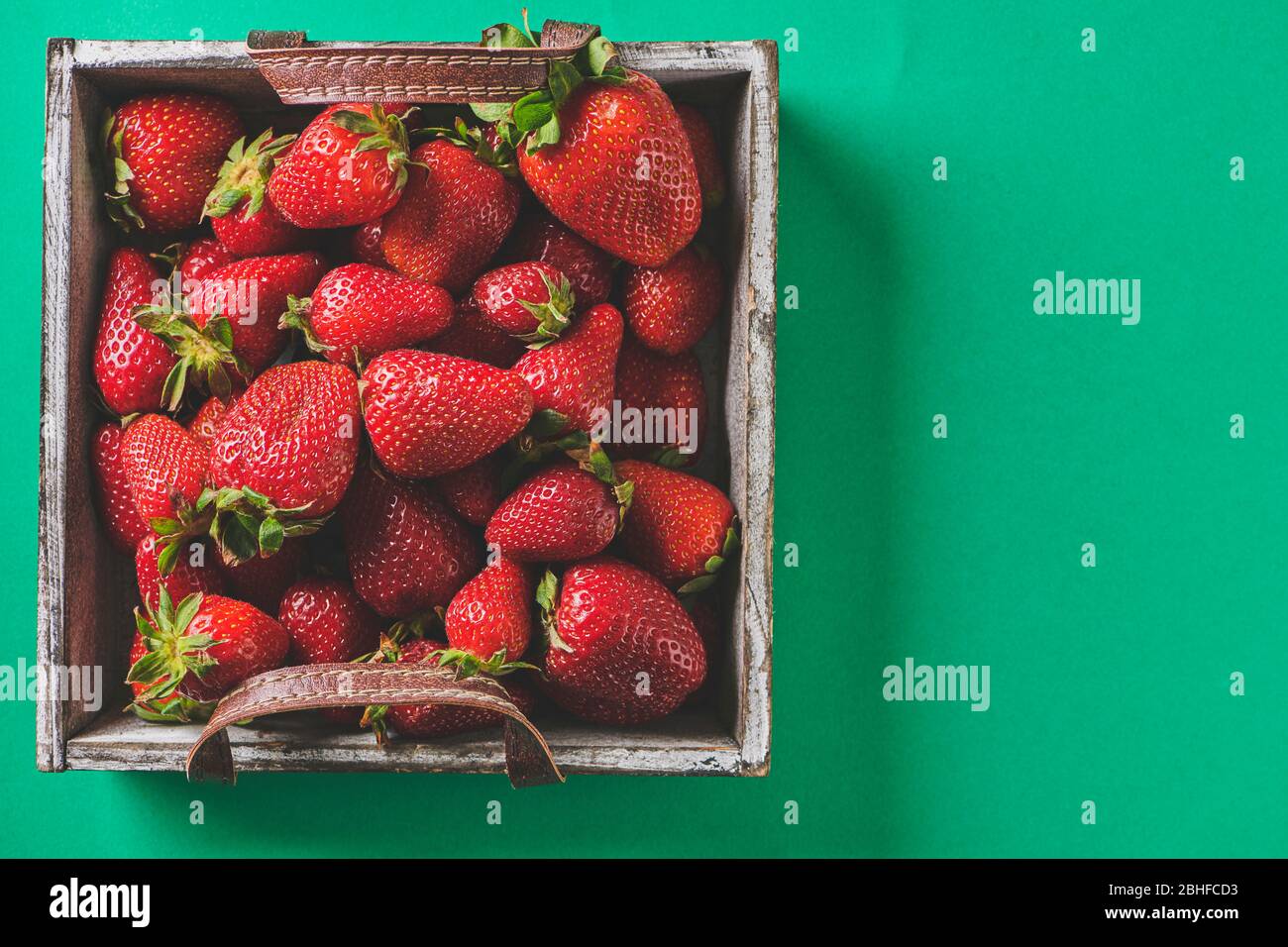 Frische rote Erdbeeren in einem Holzkorb auf grünem Hintergrund Stockfoto