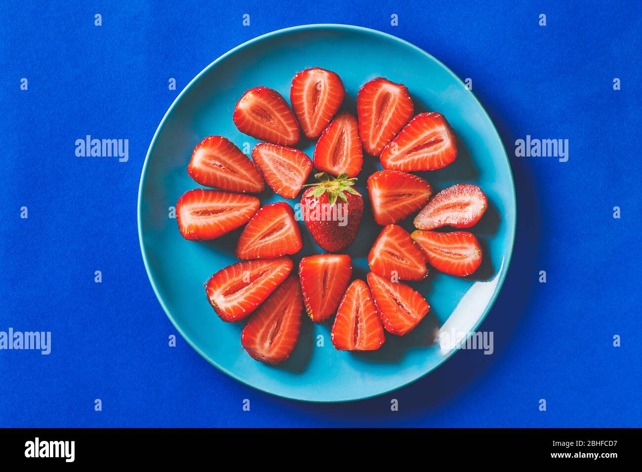 Frische Erdbeeren in einem blauen Teller auf einem dunkelblauen Karton Hintergrund Stockfoto