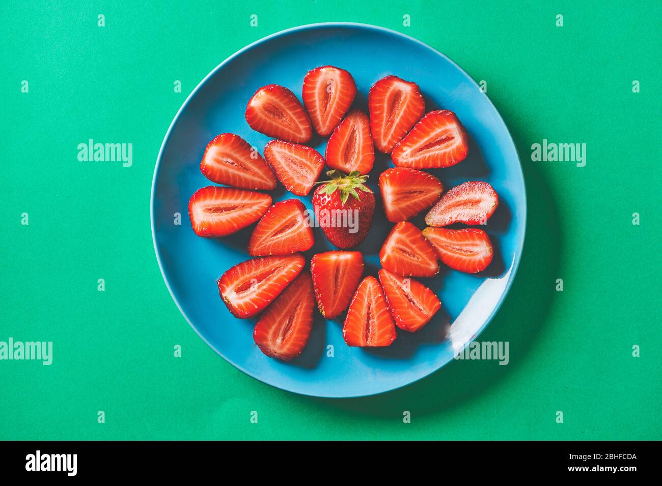 Frische Erdbeeren in einem blauen Teller auf einer grünen Pappe Stockfoto