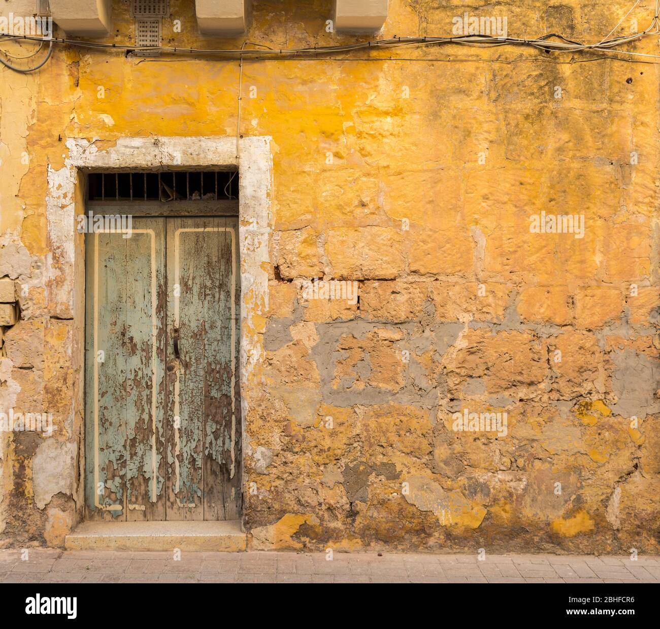 Holztür in der Wand in schlechtem Zustand, Mellieha, Malta Stockfoto