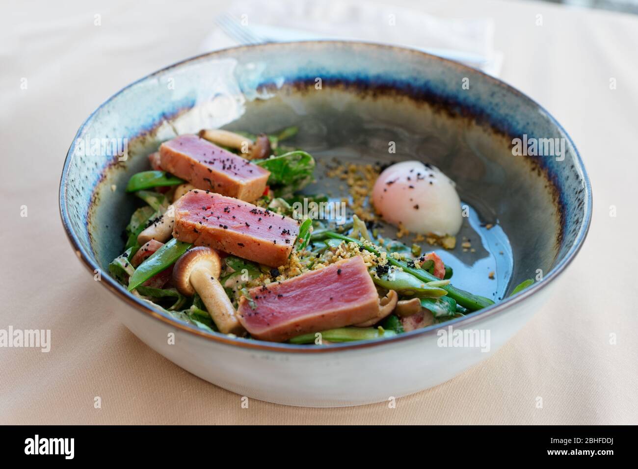 Gebratenes Thunfischfilet und grüner Erbsensalat in handgefertigtem Tonteller Stockfoto