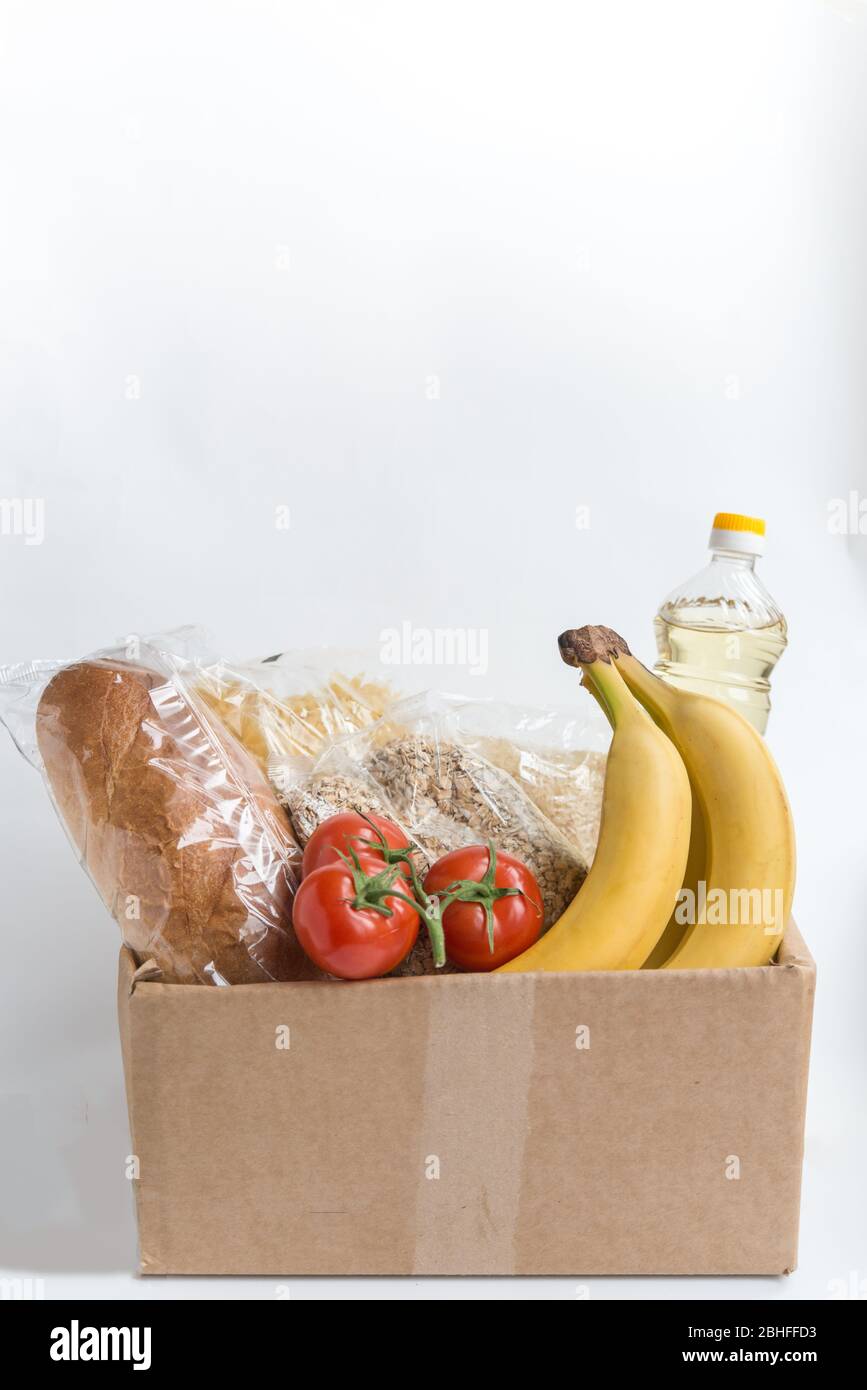 Verschiedene Lebensmittel in der Kartonbox auf dem Tisch mit Kopierplatz. Spende Lebensmittel in der Box. Obst, Öl und Getreide Stockfoto