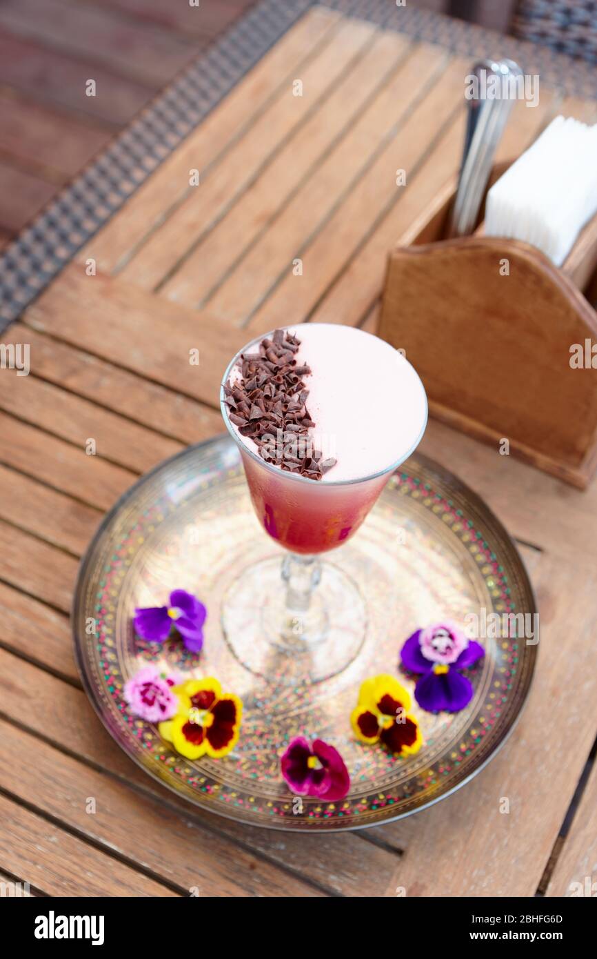 Roter Cocktail mit Schaum und Schokoladenrasur auf dem Restauranttisch Stockfoto