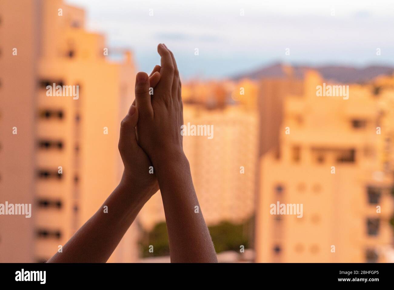 Kind klatscht Hände, applaudieren vom Balkon, um Ärzte, Krankenschwestern, Krankenhausmitarbeiter während der Coronavirus-Pandemie Quarantäne zu unterstützen Stockfoto