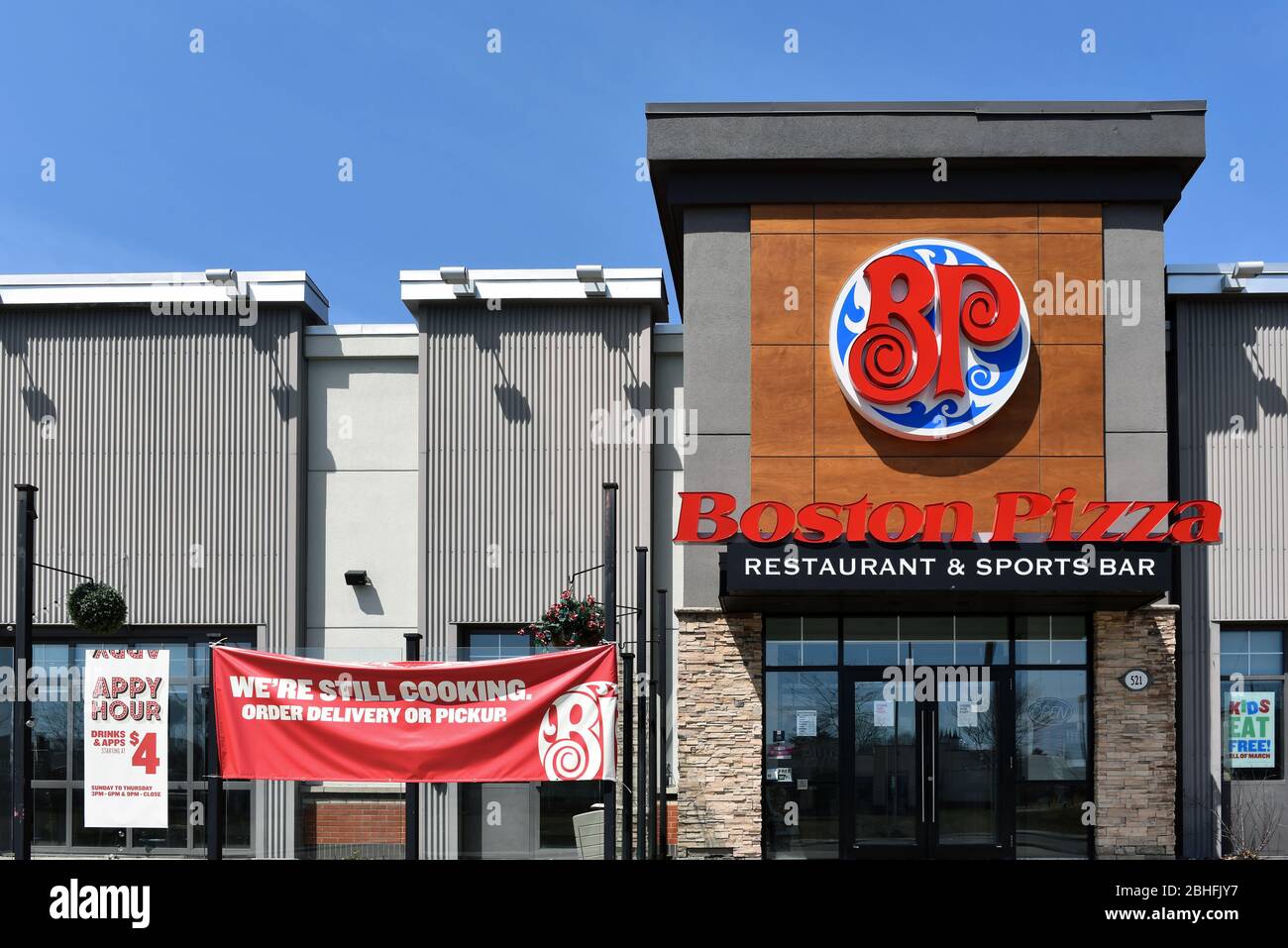 Boston Pizza eine kanadische Restaurantkette mit Franchise-Angeboten in mehreren Ländern, mit Schild, das Abholung und Lieferung nur während der Sperrung anbietet Stockfoto