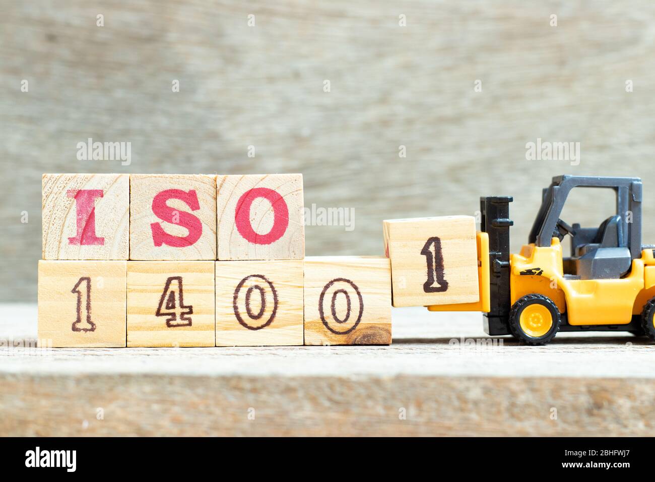 Spielzeug Gabelstapler halten Buchstabenblock 1 Wort ISO 14001 auf Holz Hintergrund zu vervollständigen Stockfoto