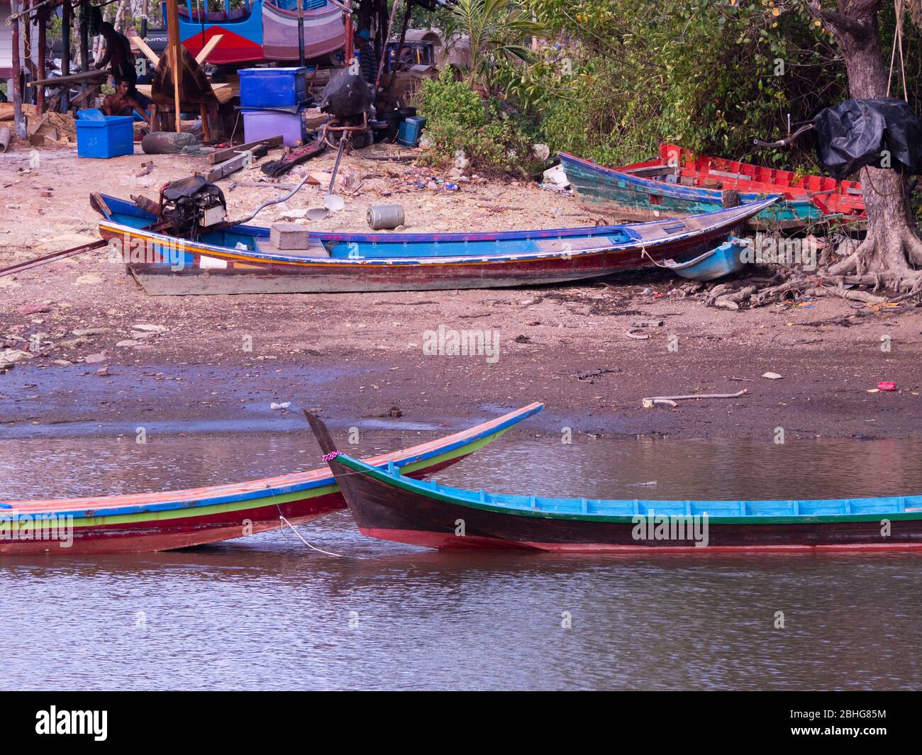 Traditionelle, hölzerne Langschwanzboote auf einer kleinen Werft am Ufer des Mak Bang, einem Kanal in Satun City, Satun im Süden Thailands. Stockfoto