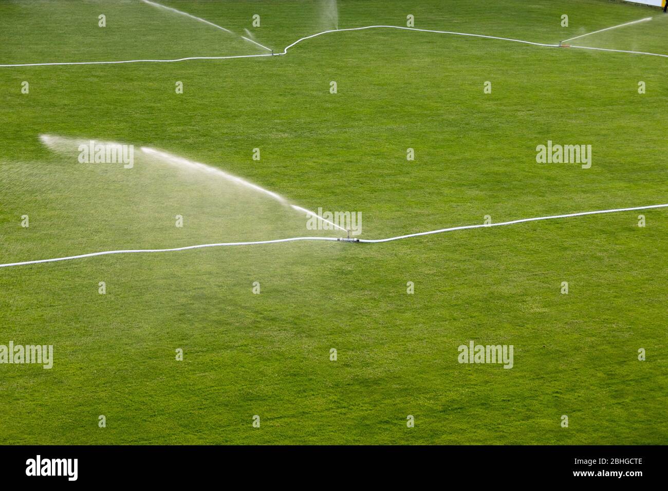 Während eines Monats mit sehr wenig bis keinem Regen werden Sprinkler gesehen, die einen trockenen Fußballplatz in Flums, Schweiz, bewässern. Stockfoto