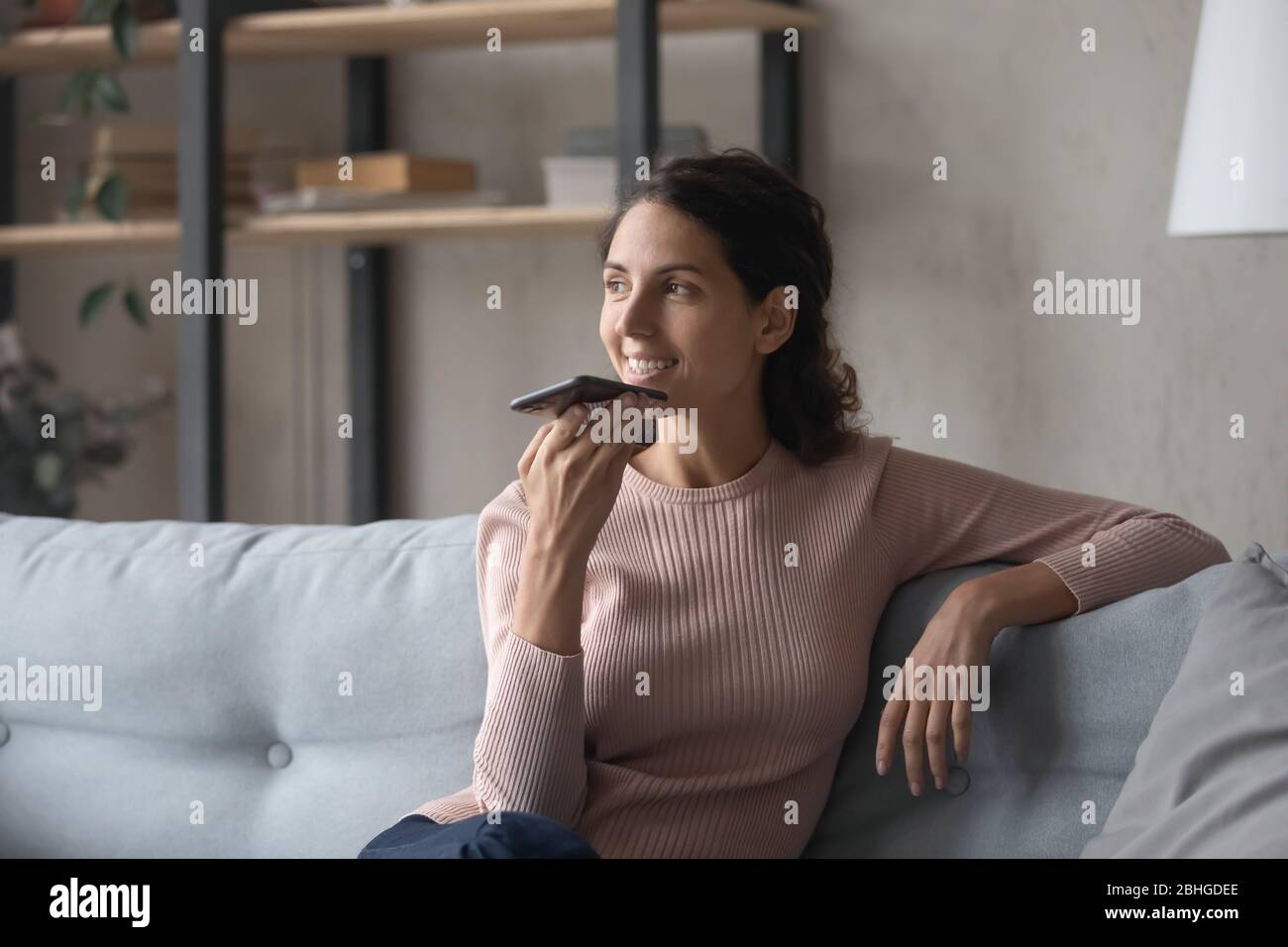 Glückliche junge Frau, die Audio-Nachricht an einen Freund sendet. Stockfoto