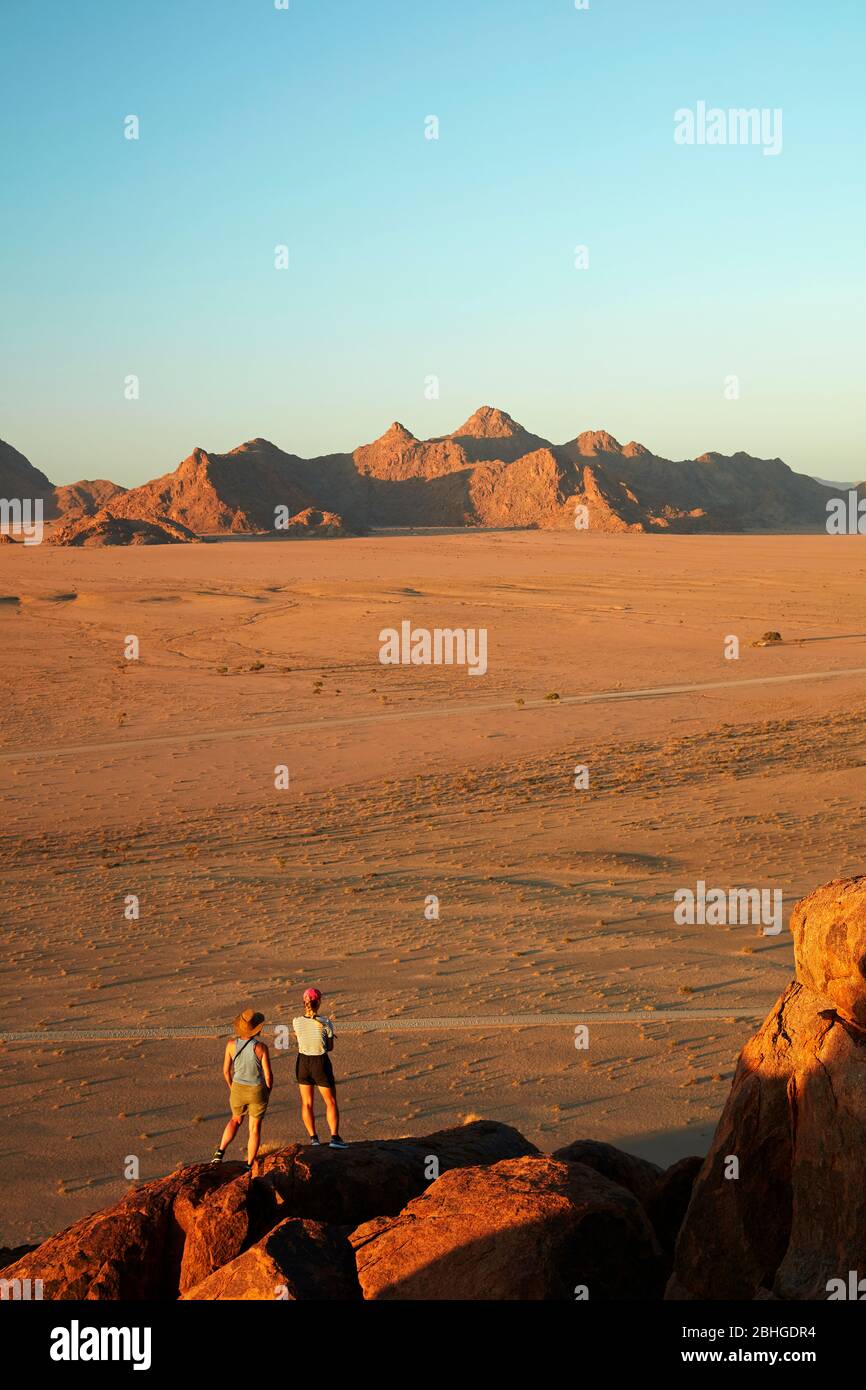 Frauen, die die Berge von oben auf einer Felsküste über Desert Camp, Sesriem, Namib Desert, Namibia, Africa betrachten (Modell veröffentlicht) Stockfoto