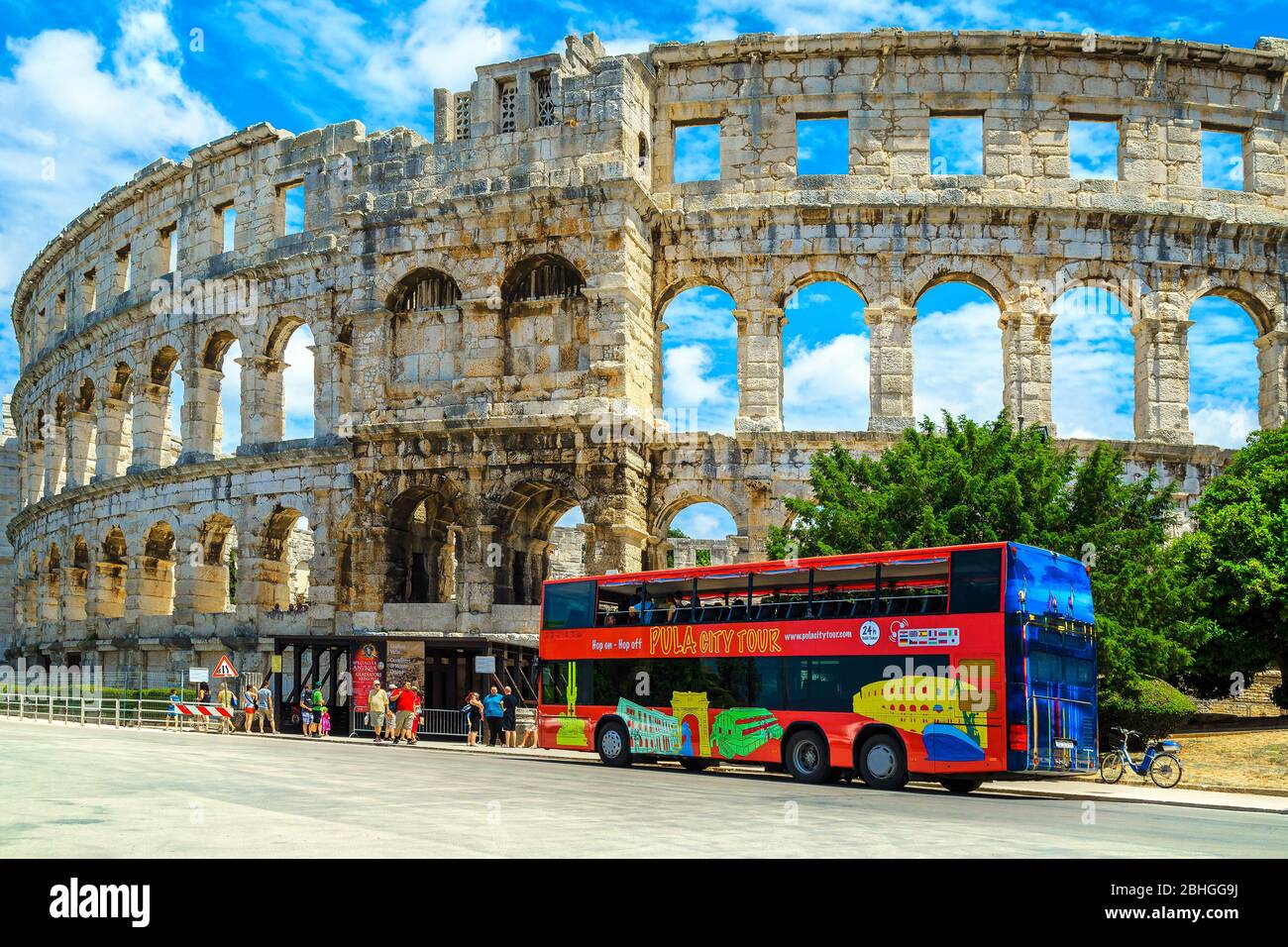 PULA, KROATIEN - 15. JUNI 2015: Beliebtes Reiseziel mit dem berühmten römischen Amphitheater (Arena) Gebäude. Bunte Sightseeing-Bus mit Touristen i Stockfoto