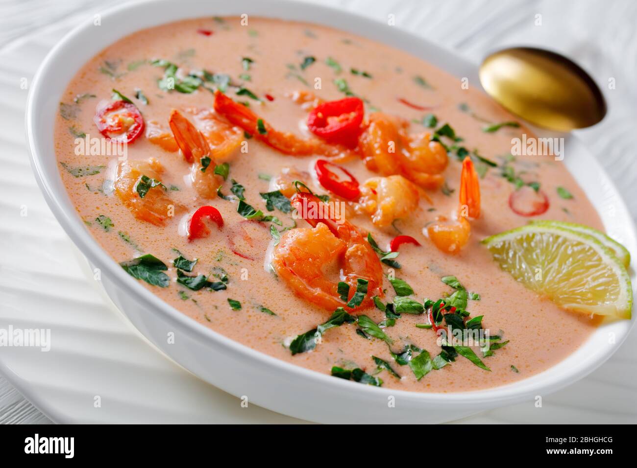 Nahaufnahme von Tom Yum Suppe, tom Kha Suppe in einer weißen Schüssel auf einem Holztisch, horizontale Ansicht von oben Stockfoto