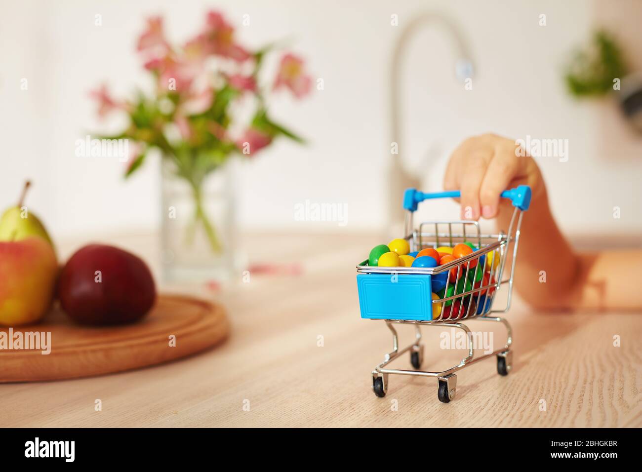 Mini-Shopping-Trolley voller Süßigkeiten auf dem Küchentischtisch Stockfoto