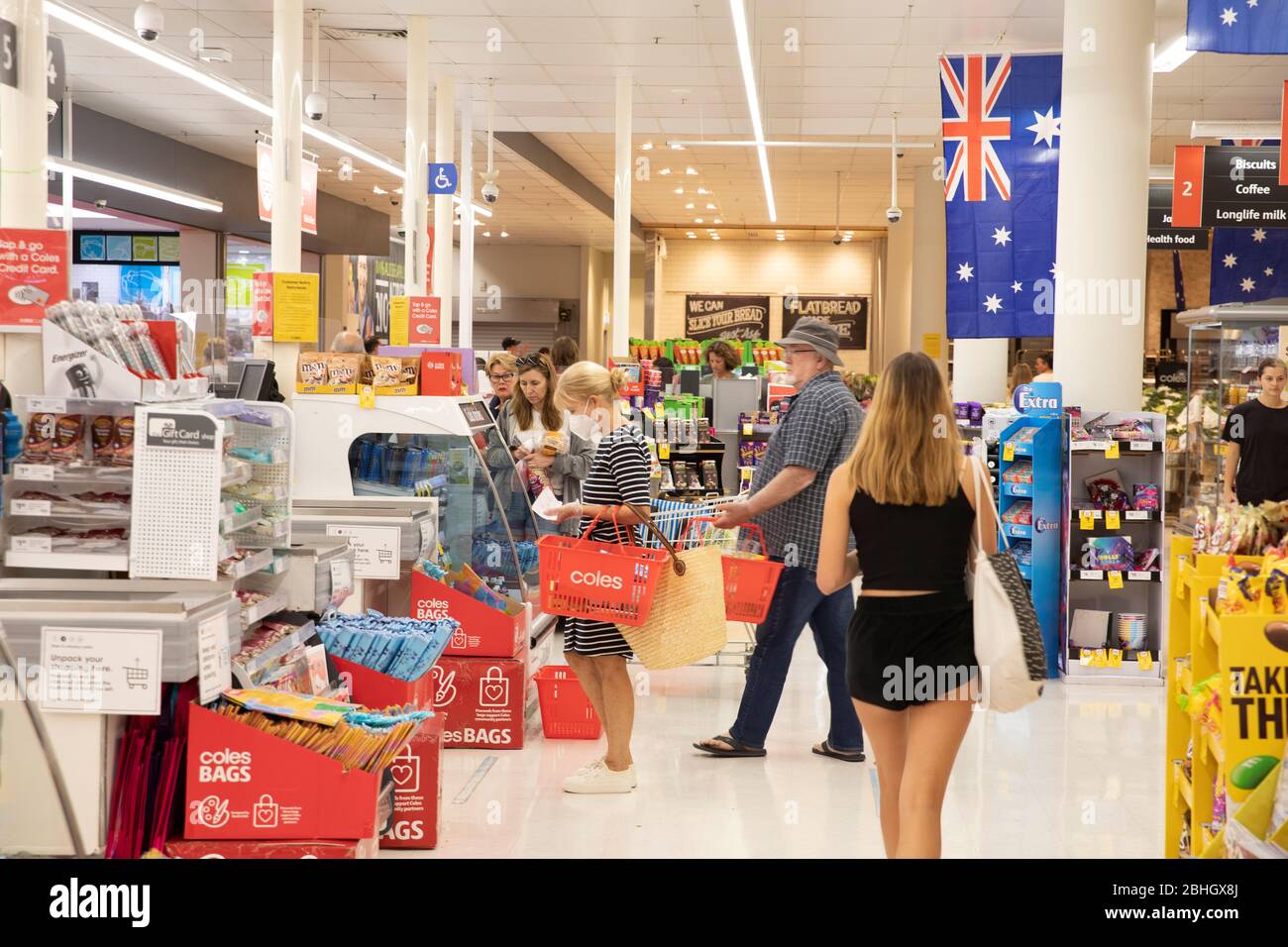 Australischer Supermarkt und Frau an der Kasse trägt Gesichtsmaske aufgrund von covid 19, Sydney, australische Flagge im Geschäft Stockfoto