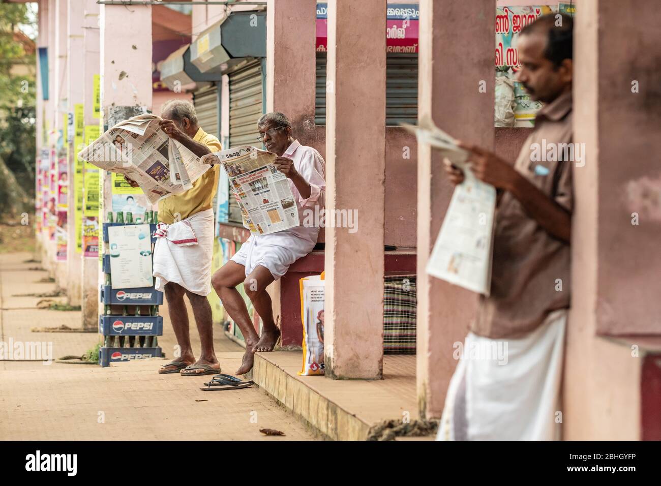 Unbekannte indische Männer lesen Zeitungen draußen in Kerala, Südindien Stockfoto