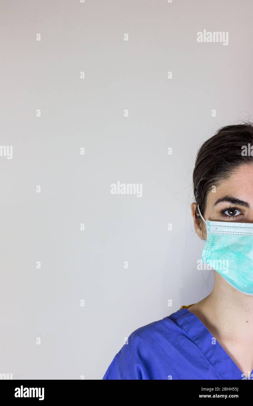 Ärztin im Arbeitsschlafanzug mit Maske zum Atemschutz vor Coronavirus. An der Seite leer. Stockfoto